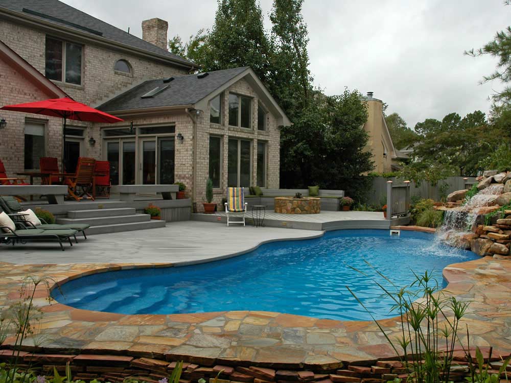 Latham-Fiberglass-Pool-Viking-Cancun curvy inground fiberglass pool with side walkin steps and a large stone waterfall feature that spills into the end of the pool
